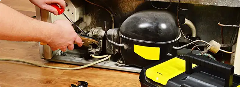 Refrigerator repair technician fixing the compressor and wiring in Mobile, AL